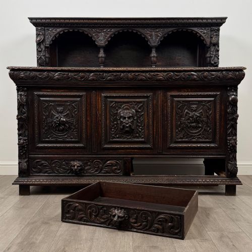 fig 10. A dark oak 19th-century sideboard featuring deep relief carvings of Green Man mythical faces, foliate motifs, lion masks, and an arched upper gallery shelf.