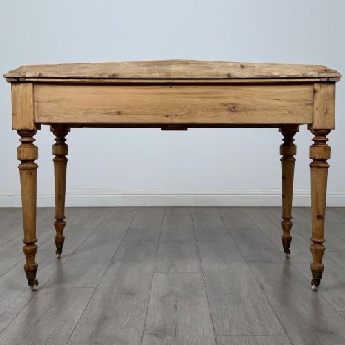 fig 4. A 19th-century Victorian pine writing table featuring two drawers with brass handles, turned wooden legs, and ceramic castors.