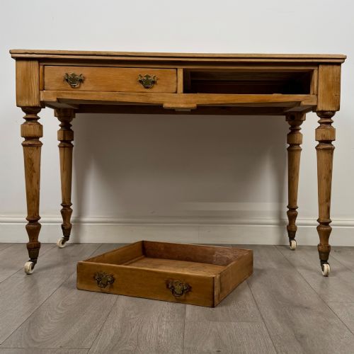 fig 9. A 19th-century Victorian pine writing table featuring two drawers with brass handles, turned wooden legs, and ceramic castors.