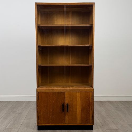 fig 1. A tall vintage golden oak display cabinet featuring glazed sliding doors on top and a two-door cupboard base.