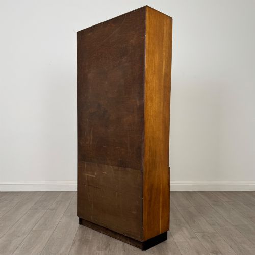 fig 7. A tall vintage golden oak display cabinet featuring glazed sliding doors on top and a two-door cupboard base.