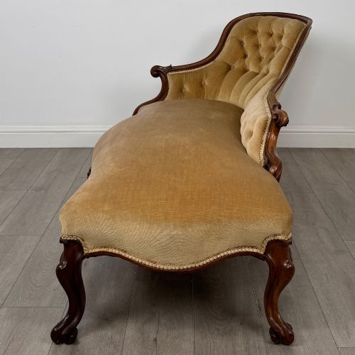 fig 2. A Victorian mahogany chaise longue featuring ochre velvet button-backed upholstery, carved trim, and cabriole legs.