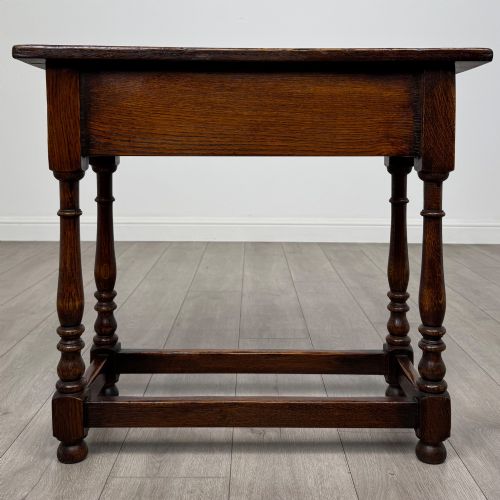 fig 4. A dark oak side table featuring a single drawer with brass drop handles, turned legs, and a perimeter box stretcher.