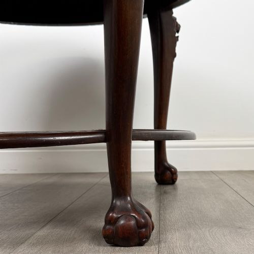 fig 6. A circular dark mahogany coffee table featuring carved lion heads atop cabriole legs ending in claw and ball feet, with a woven cane lower shelf.