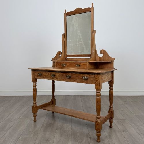 fig 1. A Victorian pitch pine dressing table featuring a central swivel mirror, side scroll shelves, frieze drawers with brass handles, and turned legs with a low shelf.