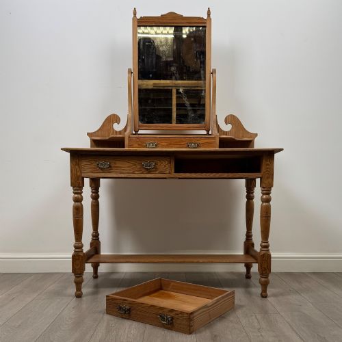 fig 9. A Victorian pitch pine dressing table featuring a central swivel mirror, side scroll shelves, frieze drawers with brass handles, and turned legs with a low shelf.