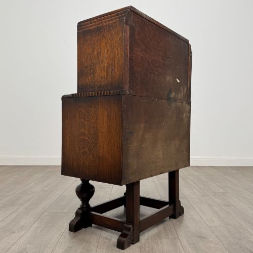 fig 4. An early 20th-century dark oak writing bureau featuring a sloped fall-front lid above two drawers, supported on turned bulbous legs with stretchers.