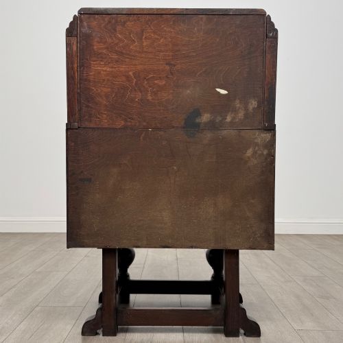 fig 5. An early 20th-century dark oak writing bureau featuring a sloped fall-front lid above two drawers, supported on turned bulbous legs with stretchers.