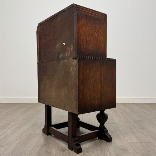 fig 6. An early 20th-century dark oak writing bureau featuring a sloped fall-front lid above two drawers, supported on turned bulbous legs with stretchers.