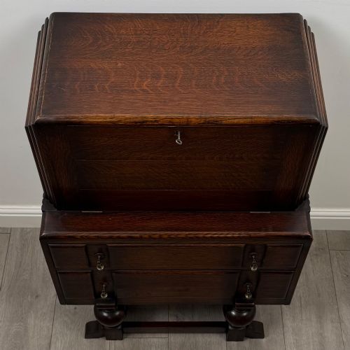 fig 9. An early 20th-century dark oak writing bureau featuring a sloped fall-front lid above two drawers, supported on turned bulbous legs with stretchers.