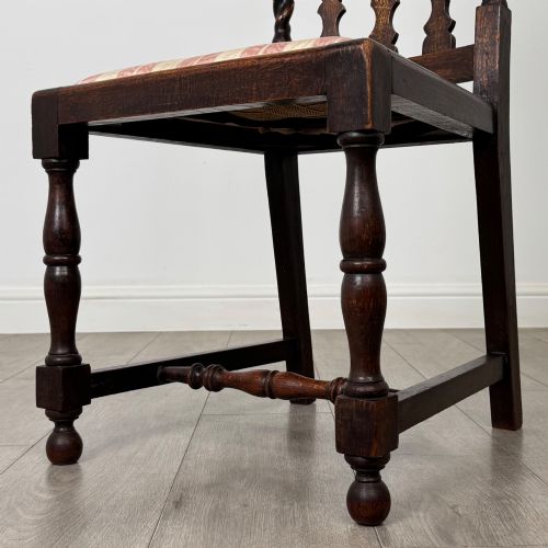 fig 4. A set of four dark oak dining chairs with barley twist side supports, carved top crests, vertically slatted backrests, and striped fabric seat cushions.