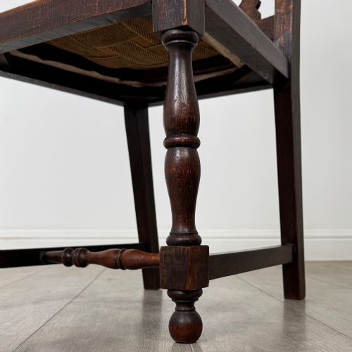 fig 5. A set of four dark oak dining chairs with barley twist side supports, carved top crests, vertically slatted backrests, and striped fabric seat cushions.