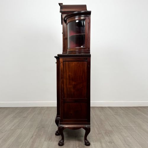 fig 3. A 19th-century Queen Anne style dark walnut display cabinet featuring curved glass side sections, an arched central glazed door with a carved shell crest, and cabriole legs.