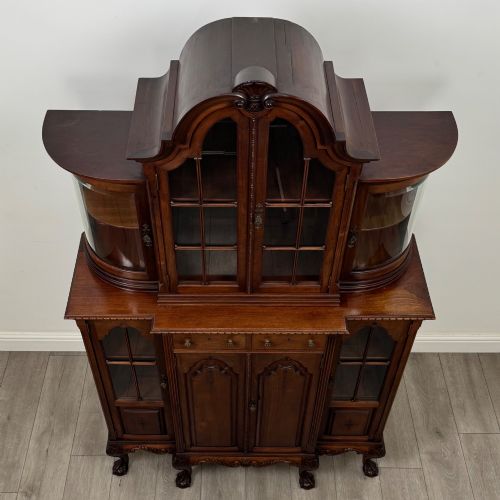 fig 9. A 19th-century Queen Anne style dark walnut display cabinet featuring curved glass side sections, an arched central glazed door with a carved shell crest, and cabriole legs.