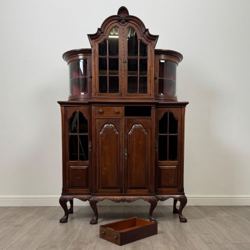 fig 10. A 19th-century Queen Anne style dark walnut display cabinet featuring curved glass side sections, an arched central glazed door with a carved shell crest, and cabriole legs.