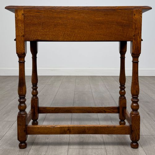 fig 4. A golden oak side table featuring a single drawer with two brass handles, turned legs, and an lower stretcher base.