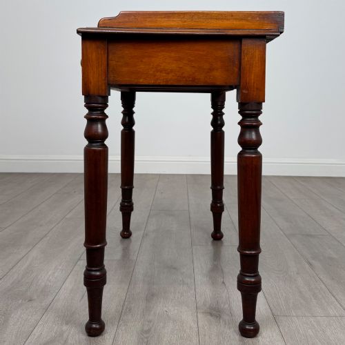 fig 2. A Victorian mahogany writing table featuring two frieze drawers with brass knob handles, turned legs, and a low gallery back.