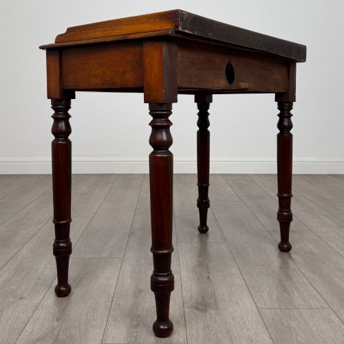 fig 3. A Victorian mahogany writing table featuring two frieze drawers with brass knob handles, turned legs, and a low gallery back.