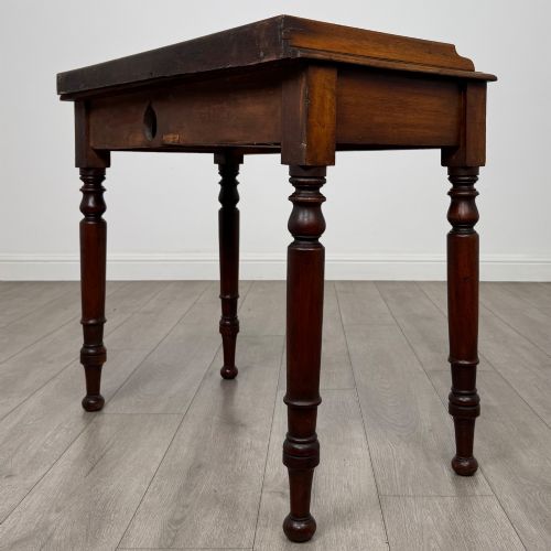 fig 5. A Victorian mahogany writing table featuring two frieze drawers with brass knob handles, turned legs, and a low gallery back.