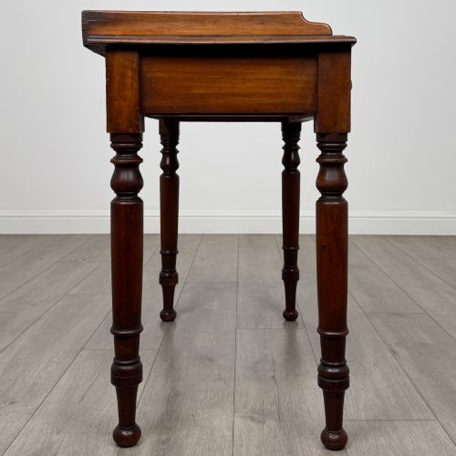 fig 6. A Victorian mahogany writing table featuring two frieze drawers with brass knob handles, turned legs, and a low gallery back.