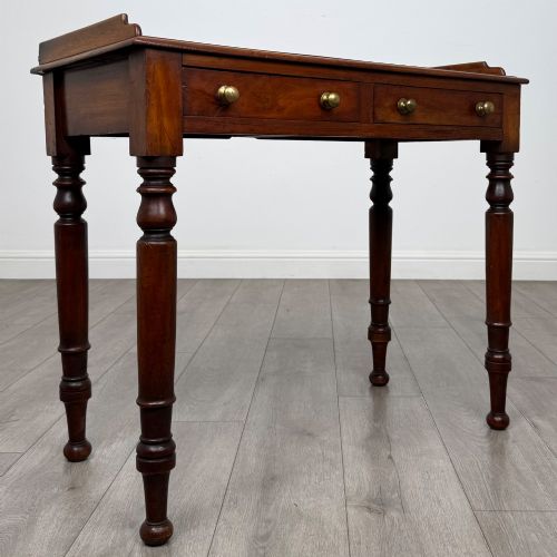 fig 7. A Victorian mahogany writing table featuring two frieze drawers with brass knob handles, turned legs, and a low gallery back.
