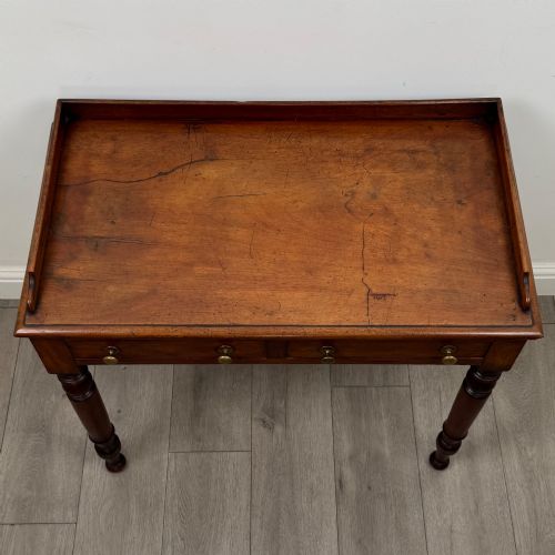 fig 8. A Victorian mahogany writing table featuring two frieze drawers with brass knob handles, turned legs, and a low gallery back.