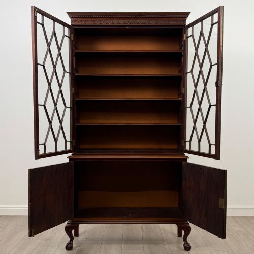 fig 1. A 20th-century Chippendale style mahogany bookcase featuring two upper glazed doors with diamond pattern astragal glazing and a two-door cupboard base raised on cabriole legs with claw and ball feet.
