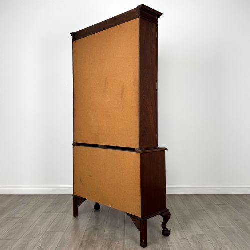 fig 6. A 20th-century Chippendale style mahogany bookcase featuring two upper glazed doors with diamond pattern astragal glazing and a two-door cupboard base raised on cabriole legs with claw and ball feet.