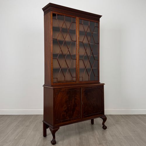 fig 8. A 20th-century Chippendale style mahogany bookcase featuring two upper glazed doors with diamond pattern astragal glazing and a two-door cupboard base raised on cabriole legs with claw and ball feet.