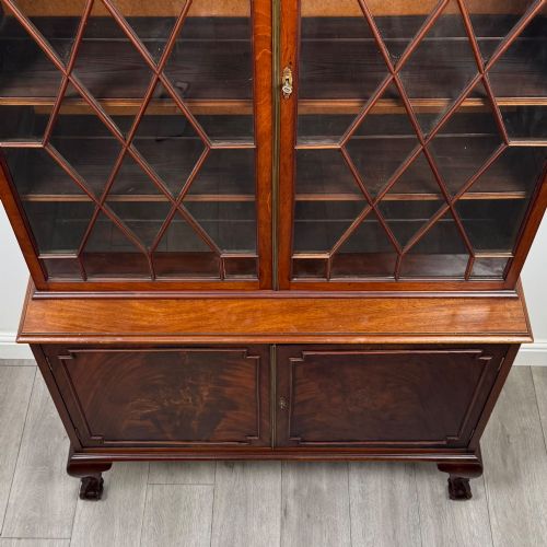 fig 9. A 20th-century Chippendale style mahogany bookcase featuring two upper glazed doors with diamond pattern astragal glazing and a two-door cupboard base raised on cabriole legs with claw and ball feet.