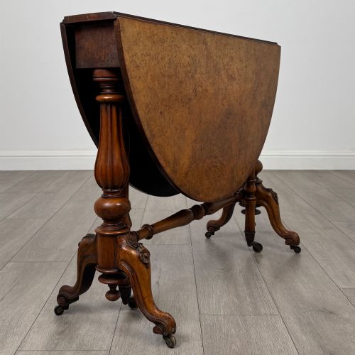 fig 5. A 19th-century Victorian Sutherland table crafted from burr walnut featuring folded drop leaves, turned twin-column supports, and carved legs on brass castors.