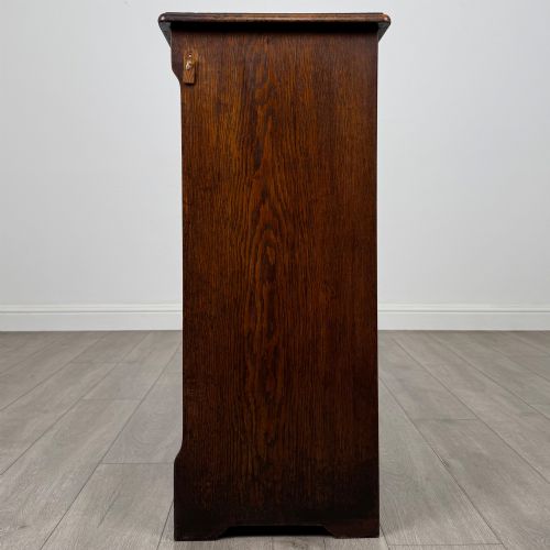 fig 3. An antique dark oak tambour cabinet featuring a vertical wooden slat roll-front door and top brass locking mechanism.
