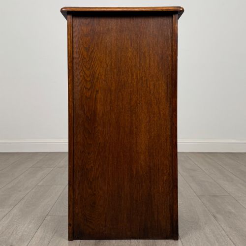 fig 5. An antique dark oak tambour cabinet featuring a vertical wooden slat roll-front door and top brass locking mechanism.