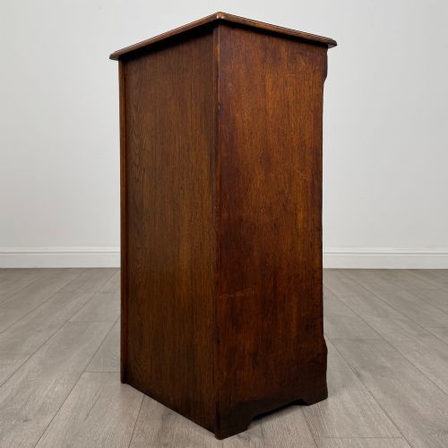 fig 6. An antique dark oak tambour cabinet featuring a vertical wooden slat roll-front door and top brass locking mechanism.