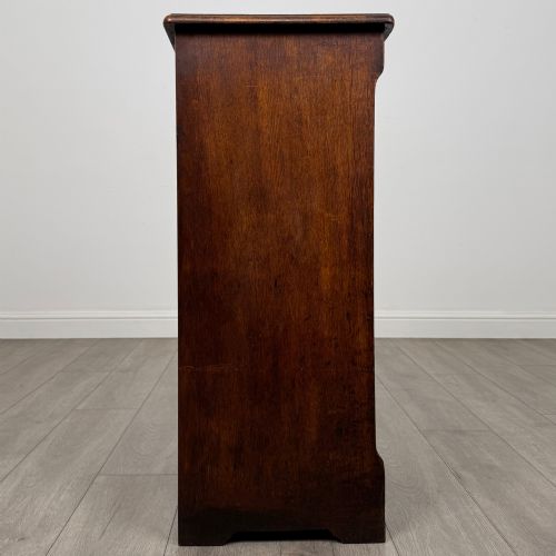 fig 7. An antique dark oak tambour cabinet featuring a vertical wooden slat roll-front door and top brass locking mechanism.