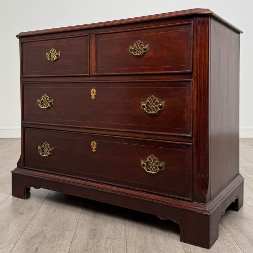fig 1. A 20th-century American mahogany chest of drawers featuring two small top drawers, two full-width lower drawers, brass bail handles, fluted quarter-columns, and bracket feet.