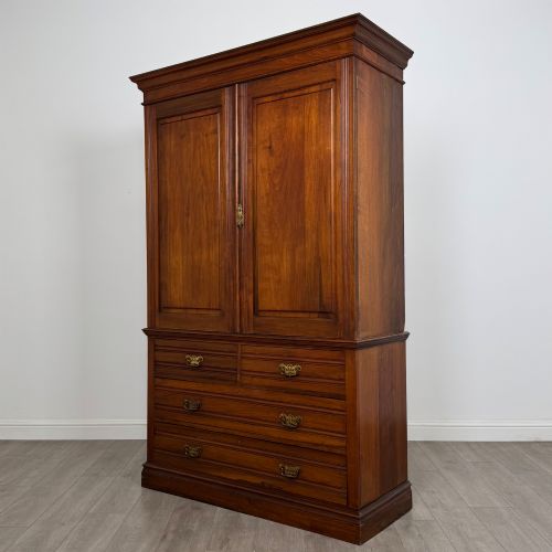 fig 2. An Edwardian walnut linen press featuring a moulded top cornice, two large upper recessed panel doors, and a lower chest of drawers with brass drop handles.