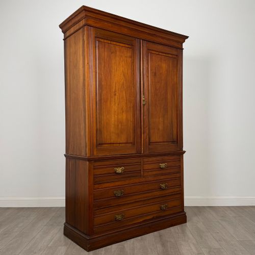 fig 8. An Edwardian walnut linen press featuring a moulded top cornice, two large upper recessed panel doors, and a lower chest of drawers with brass drop handles.