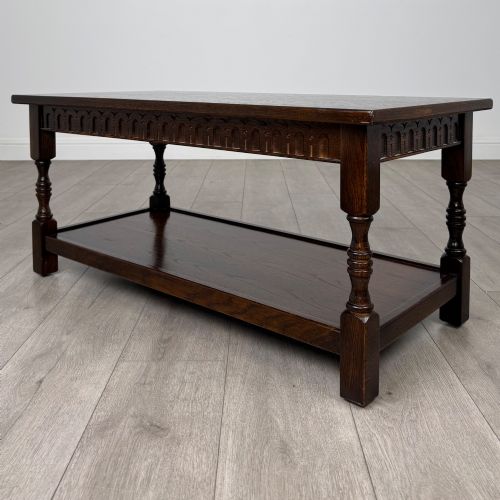 fig 1. A dark carved oak coffee table featuring an arcaded carved apron, turned legs, and an integrated lower shelf.