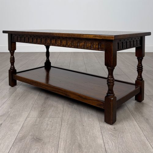 fig 4. A dark carved oak coffee table featuring an arcaded carved apron, turned legs, and an integrated lower shelf.