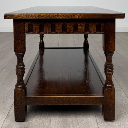 fig 5. A dark carved oak coffee table featuring an arcaded carved apron, turned legs, and an integrated lower shelf.