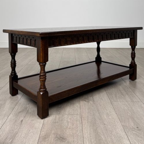 fig 6. A dark carved oak coffee table featuring an arcaded carved apron, turned legs, and an integrated lower shelf.