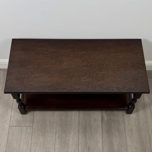 fig 7. A dark carved oak coffee table featuring an arcaded carved apron, turned legs, and an integrated lower shelf.