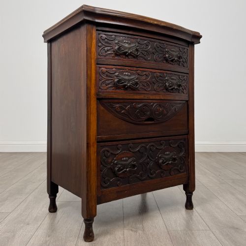 fig 7. A 19th-century Victorian walnut chest of drawers featuring ornate relief carvings across the drawer fronts and metal drop handles.