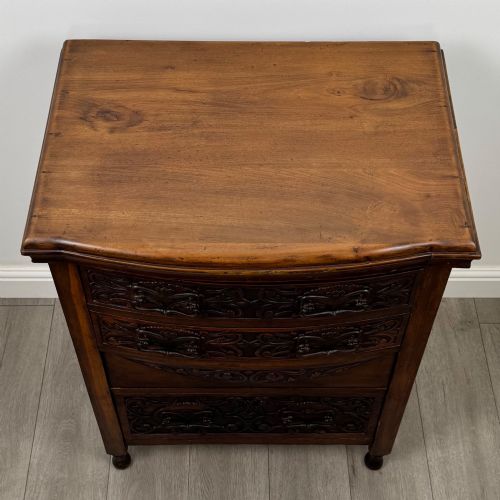 fig 8. A 19th-century Victorian walnut chest of drawers featuring ornate relief carvings across the drawer fronts and metal drop handles.