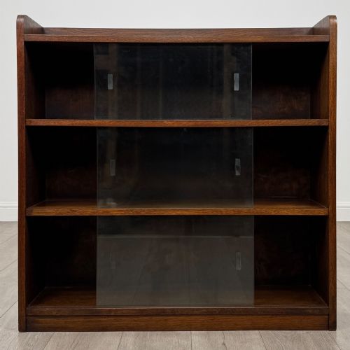 fig 1. A mid-twentieth-century dark oak display cabinet featuring three interior shelf tiers enclosed by sliding glass doors.