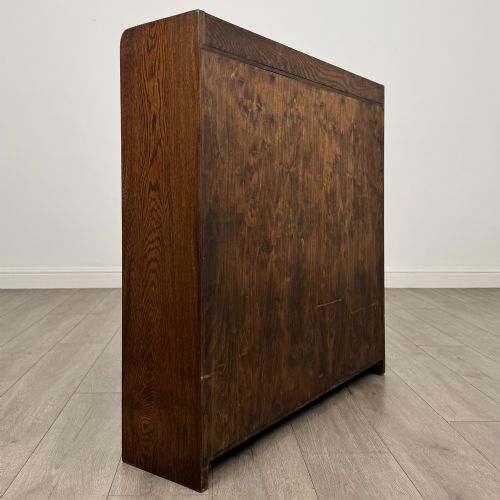 fig 4. A mid-twentieth-century dark oak display cabinet featuring three interior shelf tiers enclosed by sliding glass doors.