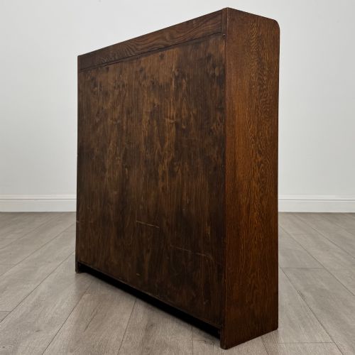 fig 6. A mid-twentieth-century dark oak display cabinet featuring three interior shelf tiers enclosed by sliding glass doors.