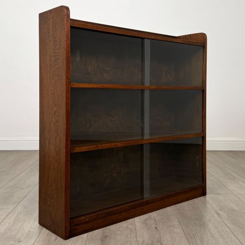 fig 8. A mid-twentieth-century dark oak display cabinet featuring three interior shelf tiers enclosed by sliding glass doors.
