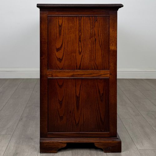 fig 7. A large medium brown oak sideboard featuring four upper drawers with brass handles above four cupboard doors with arched wood panels.